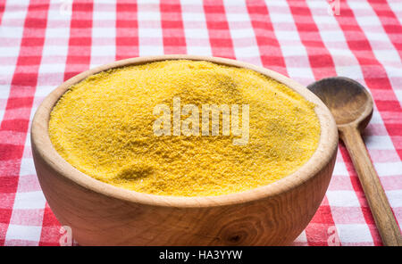 Corn flour in a wooden bowl on red white tablecloth Stock Photo