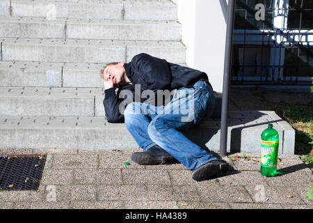 Drunken man lying on pavement asleep in the street in front of ironic ...