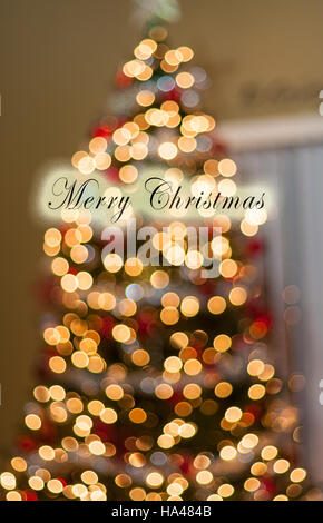 Single Red Happy Holidays Ornament hanging in front of lights Stock Photo