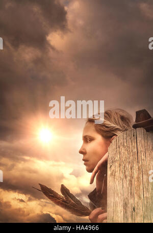 a young woman standing in nature holding three bird feathers Stock Photo