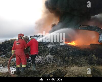 Qayyarah, Iraq. 26th November, 2016. Oil company workers try to put off fire at an oil well in Qayyarah town, south of Mosul, in northern Iraq, on Nov. 26, 2016. Qayyarah town is seized by the Islamic State (IS) militants in June of 2014. The IS militants bombed all oil wells here when Iraqi army recaptured the town in August this year. The army started military operations to retake Mosul city on Oct. 17, since when the government organized oil companies to put off the fire. Credit:  Xinhua/Alamy Live News Stock Photo