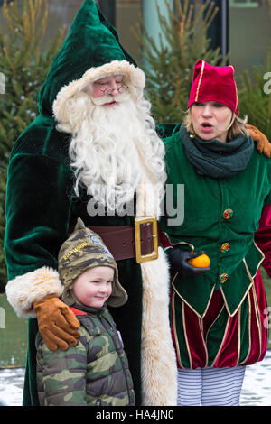 Portsmouth, Hampshire, UK 27 November 2016. Thousands visit the Victorian Festival of Christmas at Portsmouth Historic Dockyard for the entertainment, characters dressed in olden days and the Christmas market.  Father Christmas, Santa Claus, dressed in Victorian green costume and his elf helper Miss Chief and young boy. Credit:  Carolyn Jenkins/Alamy Live News Stock Photo