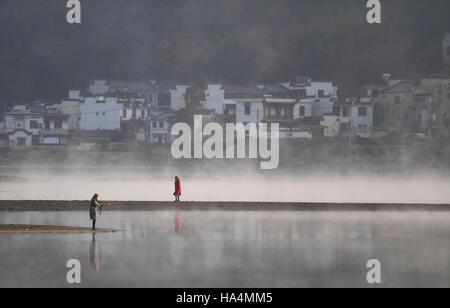 Yixian, China's Anhui Province. 28th Nov, 2016. Tourists walk by fog-enveloped Qishu Lake in Yixian County of Huangshan City, east China's Anhui Province, Nov. 28, 2016. Credit:  Chen Yehua/Xinhua/Alamy Live News Stock Photo