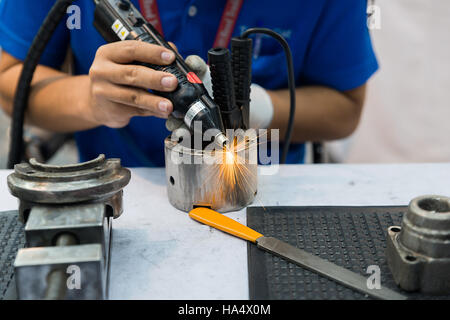 Worker using machine for coating and overlay steel for maintenance and repair in factory. Stock Photo