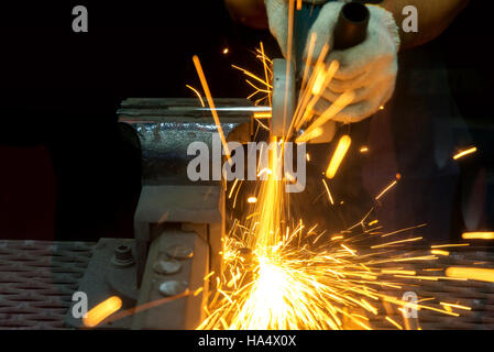 Worker cutting with grinder and welding metal with many sharp sparks in factory Stock Photo