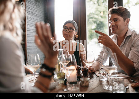 Group of friends meeting at restaurant for dinner. Young men and women having evening meal at cafe. Stock Photo