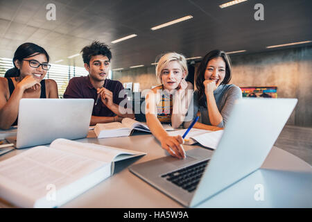 College students using laptop while sitting at table. Group study for school assignment. Stock Photo