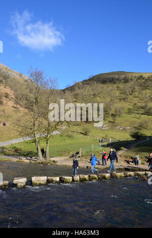 A family crossing the stepping stones at Dovedale in the Derbyshire Peak District. Stock Photo