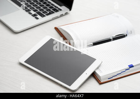 Tablet computer on desk in office with a notepad and a laptop Stock Photo