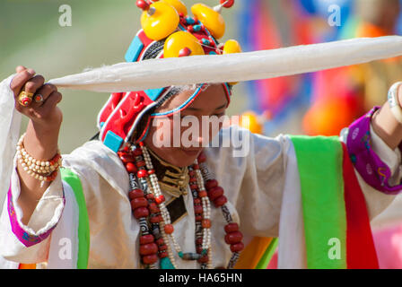 A young Khampa girl offers a silk scarf during a traditional dance at the Yushu Horse Racing Festival in Qinghai. Stock Photo