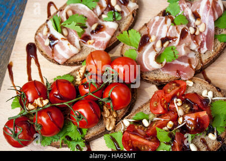 Snack of bread (baguette), bacon (ham), tomatoes, balsamic and spices. Good beer and wine.   Love for a European healthy raw food concept. Stock Photo