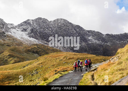 Hikers hiking on Miners' Track in Snowdon horseshoe with Y Lliwedd ahead and snow in winter.  Pen-y-Pass, Llanberis, Gwynedd, North Wales, UK Stock Photo
