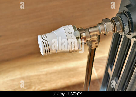 New valve on a old radiator in domestic room Stock Photo