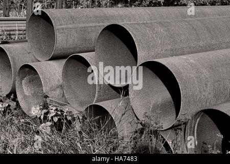 Black and white shot of rusty steel pipes found on a scrap yard. Stock Photo