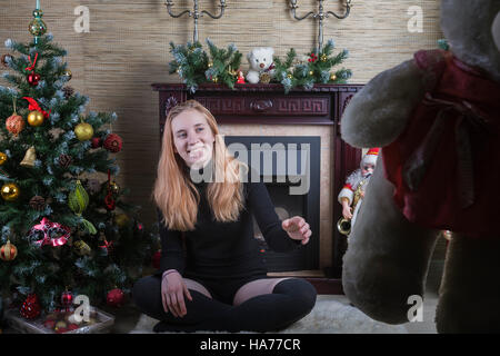 Happy young girl by the fireplace on Christmas. Stock Photo