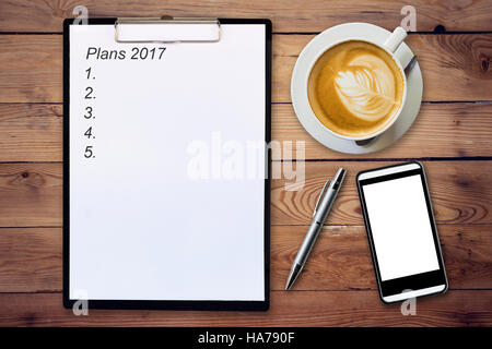 Business concept - Top view clipboard writing Plans 2017, pen, coffee cup, and phone on wood table. Stock Photo