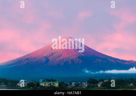 Fiery colorful sky above the red crater cone of Mount Fuji at dawn sunrise over Lake Kawaguchiko water on a summer morning Stock Photo