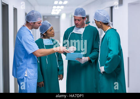 Surgeons and nurse having discussion on file in corridor Stock Photo