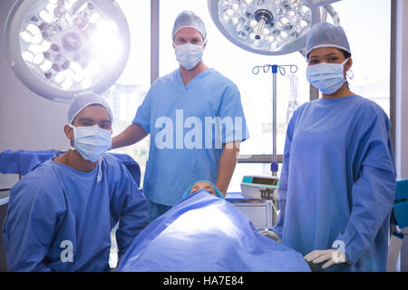 Portrait of surgeon with patient lying on bed in operation room Stock Photo