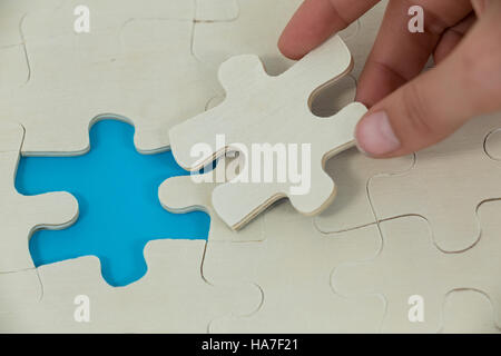 Woman placing missing piece in jigsaw puzzle Stock Photo