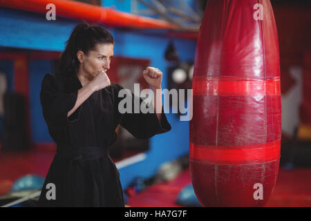 Female karate player practicing boxing with punching bag Stock Photo