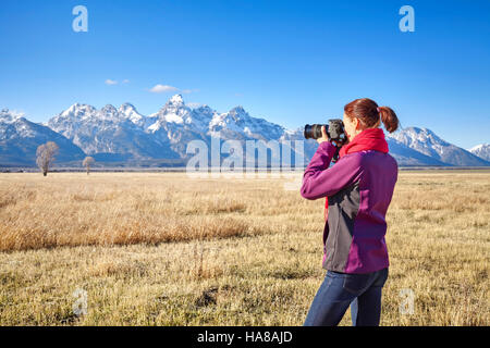 Female fit hiker taking pictures with DSLR camera in the Grand Teton National Park, Wyoming, USA. Stock Photo