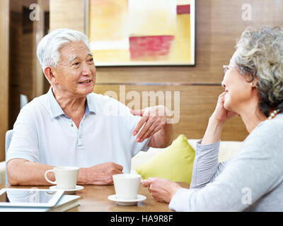 loving senior asian couple sitting at table having coffee and a heated discussion. Stock Photo