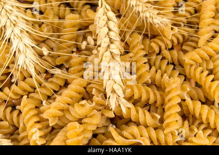 closeup of spiral shaped raw pasta with wheat Stock Photo