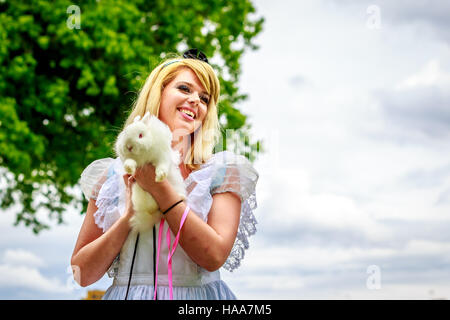 Attractive female model in Alice costume, with white rabbit, in wonderland. Stock Photo