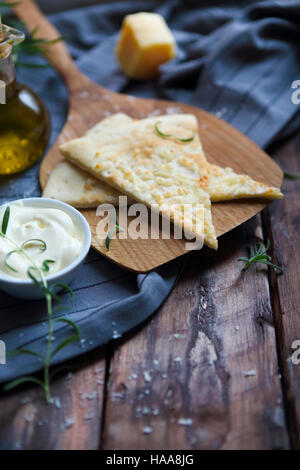 Focaccia with olive oil, parmesan cheese, white sause and rosemary. Homemade traditional Italian bread focaccia on the linen napkin. Stock Photo