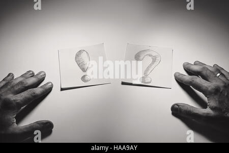 Exclamation and question signs drawn on paper, male hands in front. Stock Photo