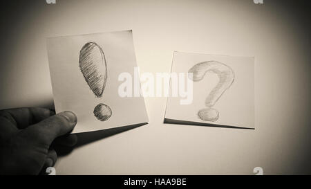 Exclamation and question signs drawn on paper, male hand is choosing a paper with exclamation, conceptual composition about having an idea or solution Stock Photo