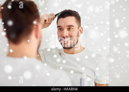 happy man brushing hair with comb at bathroom Stock Photo