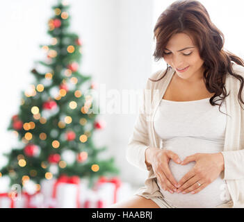 happy pregnant woman making heart gesture at home Stock Photo
