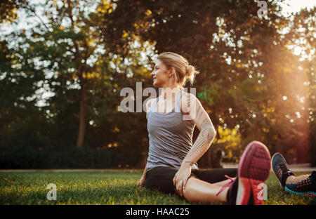 Fit young woman exercising at park. Fit young woman doing stretching workout in morning. Stock Photo