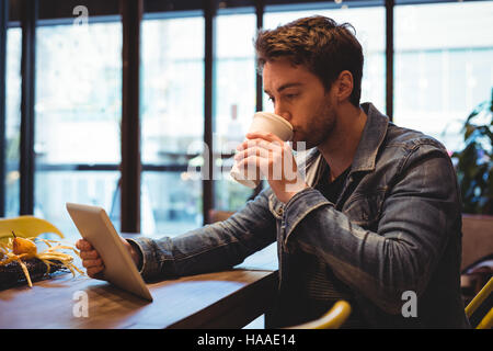 Man using digital tablet while having coffee Stock Photo
