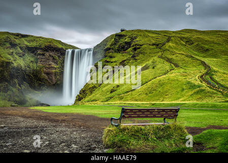 Bench at the famous Skogafoss waterfall in southern Iceland. Long exposure. Stock Photo