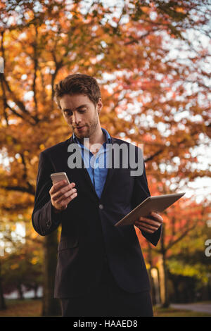 Businessman using mobile phone and holding digital tablet Stock Photo