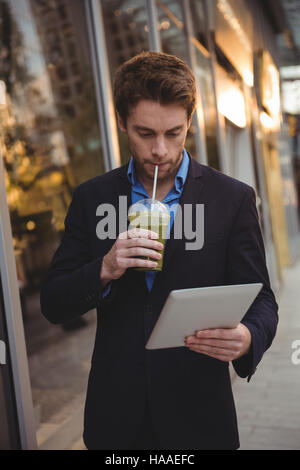 Businessman using digital tablet while having juice Stock Photo