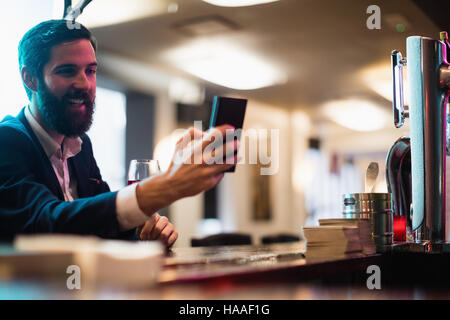 Businessman using mobile phone with glass of red wine in hand Stock Photo