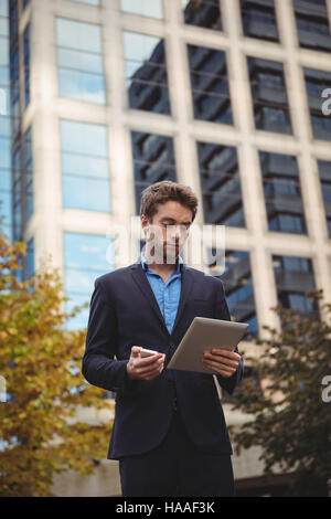 Businessman holding mobile phone and using digital tablet Stock Photo