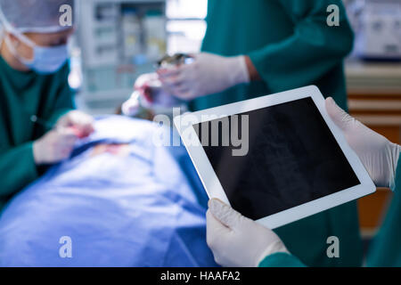 Surgeon using digital tablet while operating patient in operation theater Stock Photo