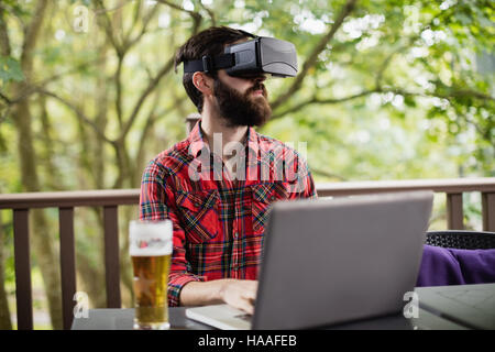 Man using virtual reality headset while using laptop Stock Photo