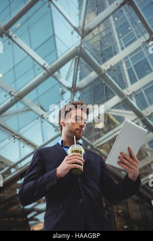 Businessman using digital tablet while having juice Stock Photo