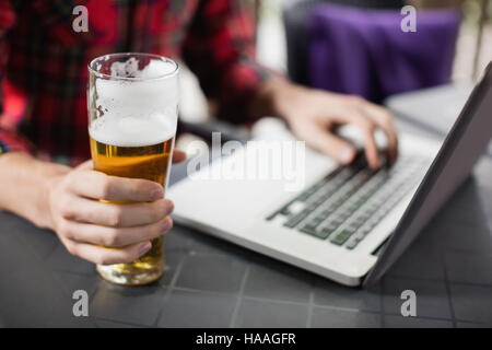 Man using laptop with glass of beer on table Stock Photo