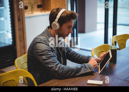 Man listening to music with headphones while using digital tablet Stock Photo