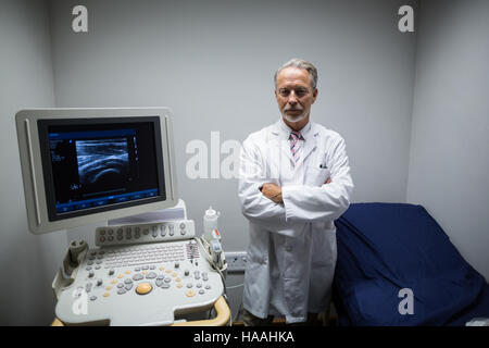 Surgeon with arms crossed standing near ultrasonic device machine Stock Photo