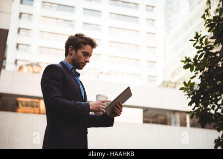 Businessman holding coffee cup and using digital tablet Stock Photo