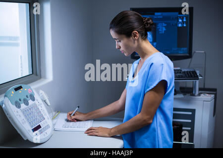 Nurse taking notes in x-ray room Stock Photo