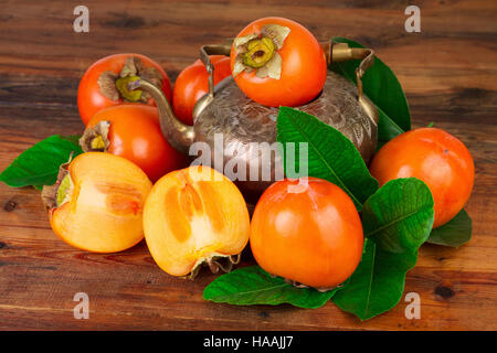 Persimmon kaki fruit with vintage tea pot. Oriental East Persian still life. Stock Photo